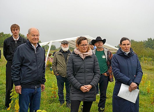 Dr. Olivia Kummel (re), Geschäftsführerin des LPV Potsdamer Kulturlandschaft, erläutert Altkanzler Olaf Scholz MdB (li) und Brandenburgs Landwirtschaftsministerin Hanka Mittelstädt MdL (Mitte) die Tätigkeit der Kooperative des LPV.