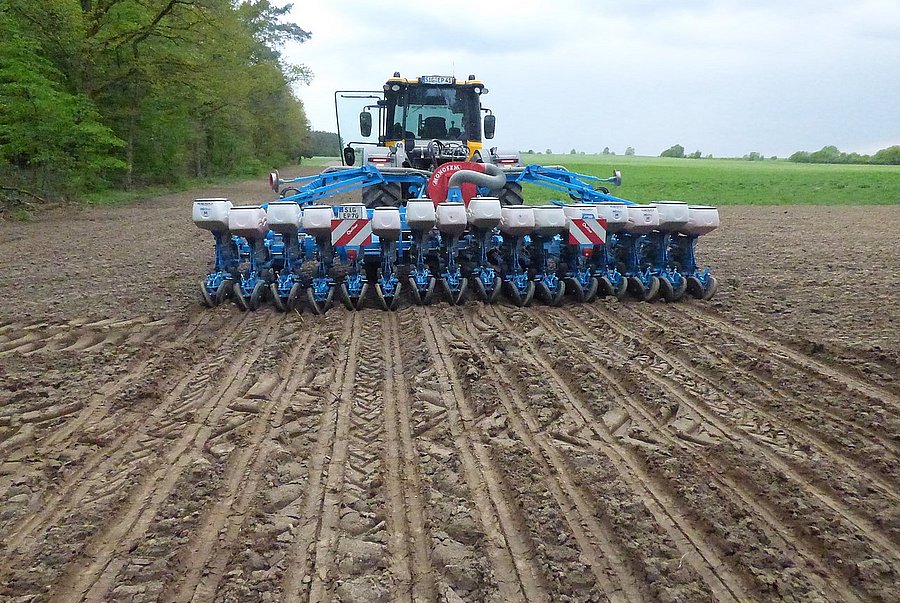 Traktor mit Aussaatgerät fährt auf Feld